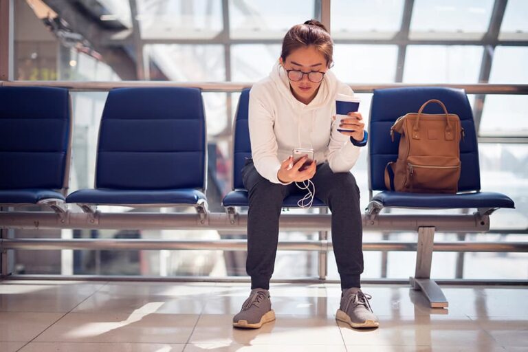 空港の待合席でスマートフォンを確認する旅行者。韓国旅行の日数と使い方に合うeSIMを選ぶ場面