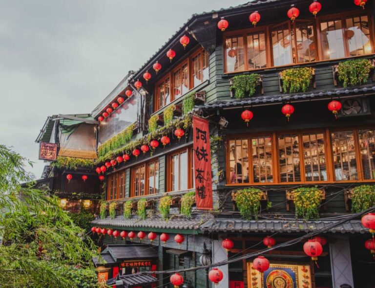 夜空に無数のオレンジ色のランタンが舞い上がる台湾のランタンフェスティバルで、観客が写真を撮ったり空を見上げたりしている様子。