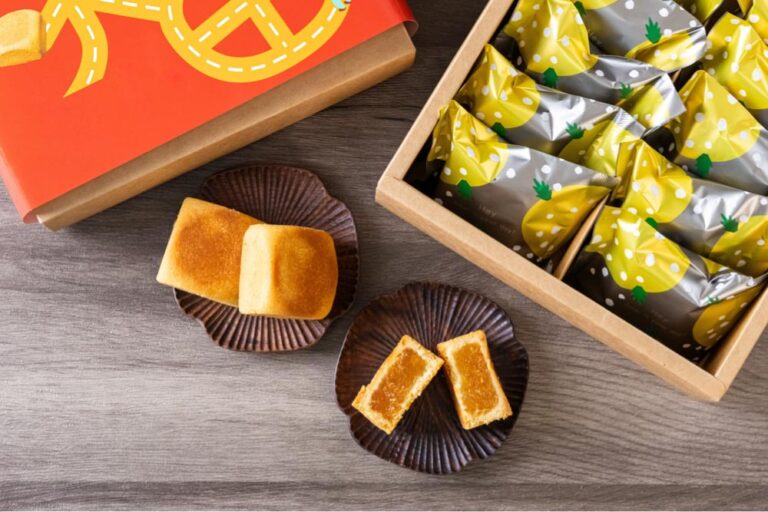 台湾土産の定番、パイナップルケーキの詰め合わせギフトボックスと、お皿に盛られた個包装と断面のケーキ。