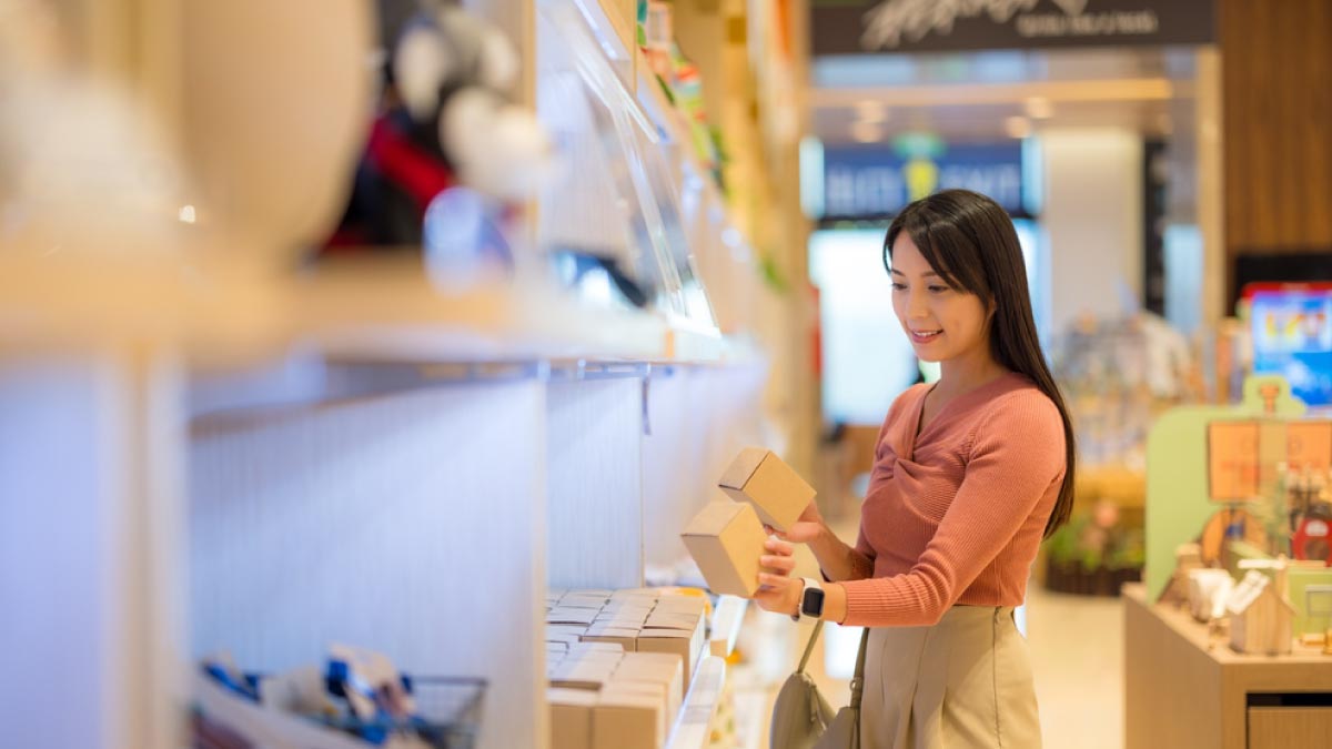 台湾の雑貨店で限定お土産を選ぶ女性、こだわりのパッケージ商品を手に取りながら人気の雑貨やお菓子を吟味する様子
