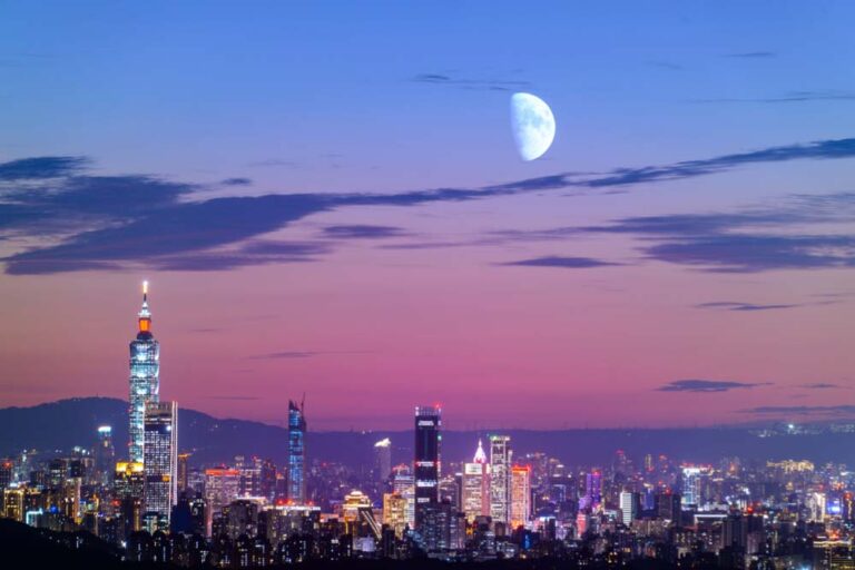 夕暮れに染まる台北の夜景と台北101、月が浮かぶ幻想的な空の風景