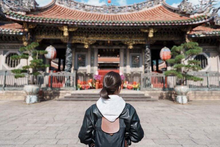 台湾・台北の龍山寺を訪れる女性観光客が伝統的な装飾の門前に立つ様子