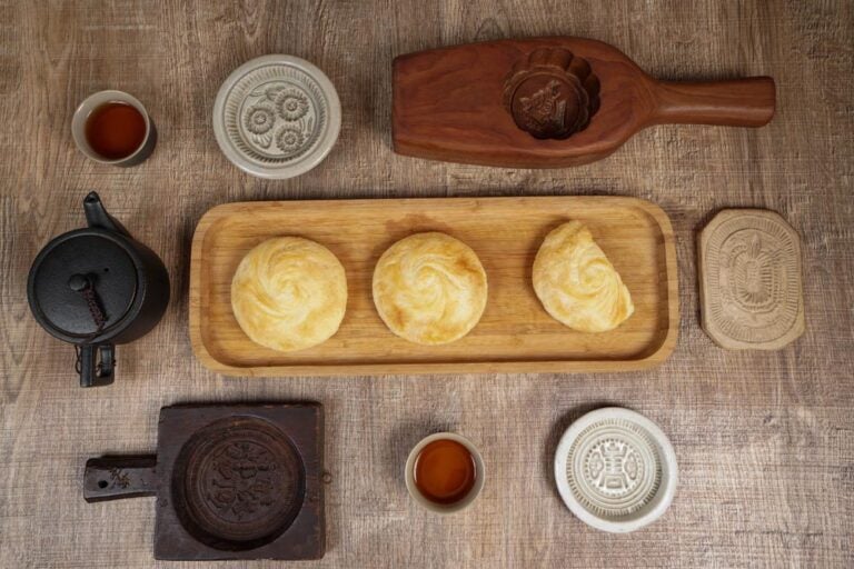 木製の型と茶器に囲まれた台湾伝統菓子「太陽餅（タイヤンピン）」が木のトレイに並ぶ、温かみあるテーブルトップの構図。