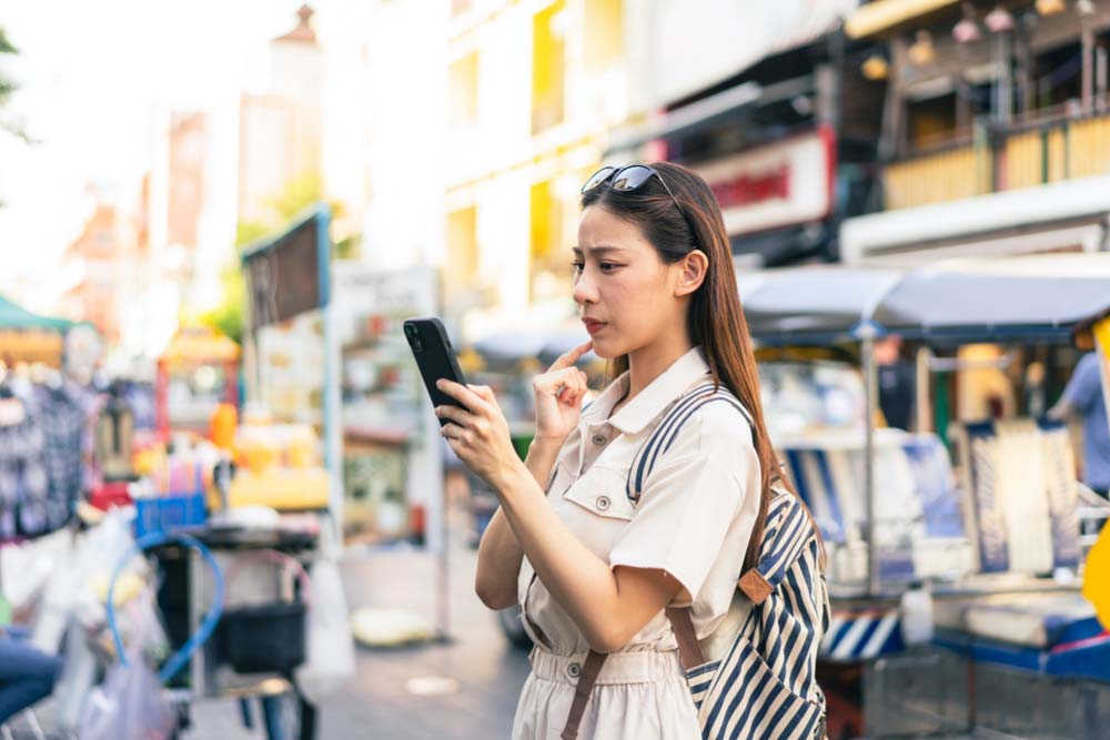 スマートフォンを見ながら道を探す観光中の女性。
