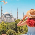 イスタンブールのブルーモスクを眺める女性観光客の後ろ姿。トルコ観光の魅力とともに、治安や安全対策を意識した旅の計画を促す記事に適した一枚。