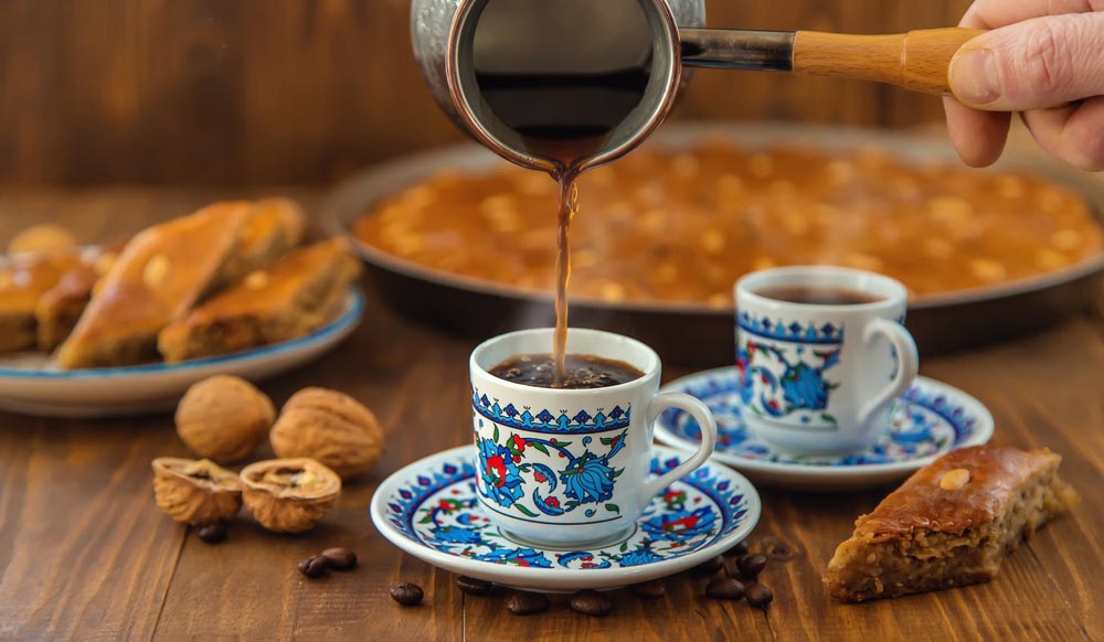 トルコの伝統的なコーヒーとバクラヴァ菓子、装飾的なカップに注がれるトルココーヒーとくるみが添えられたグルメ土産の一例