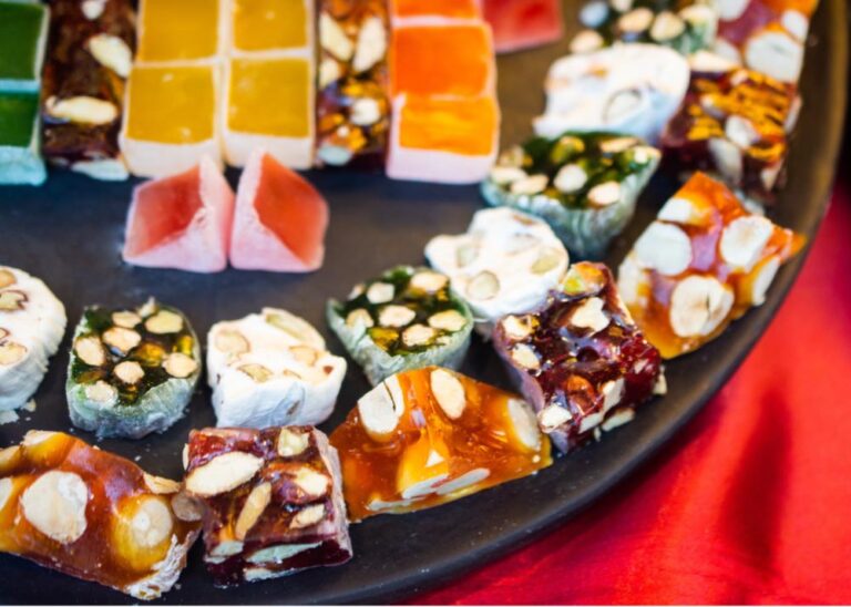 ピスタチオやナッツがたっぷり詰まった色とりどりのターキッシュディライトとヌガーが黒いプレートに美しく並べられている様子。