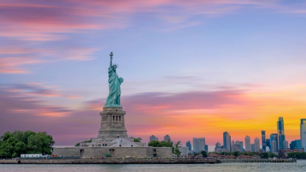 ニューヨークの夕焼け空を背景に立つ自由の女神と摩天楼の風景。