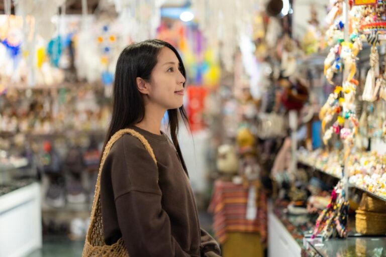 カラフルな雑貨が並ぶお土産ショップで、商品を見ながら楽しそうに歩く女性観光客。