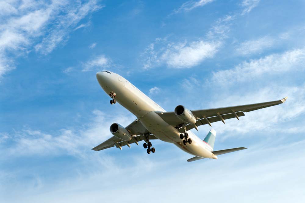 青空の下で着陸態勢に入る大型旅客機。