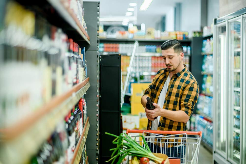 オーストラリアのスーパーマーケットで商品を確認しながら買い物をする男性。