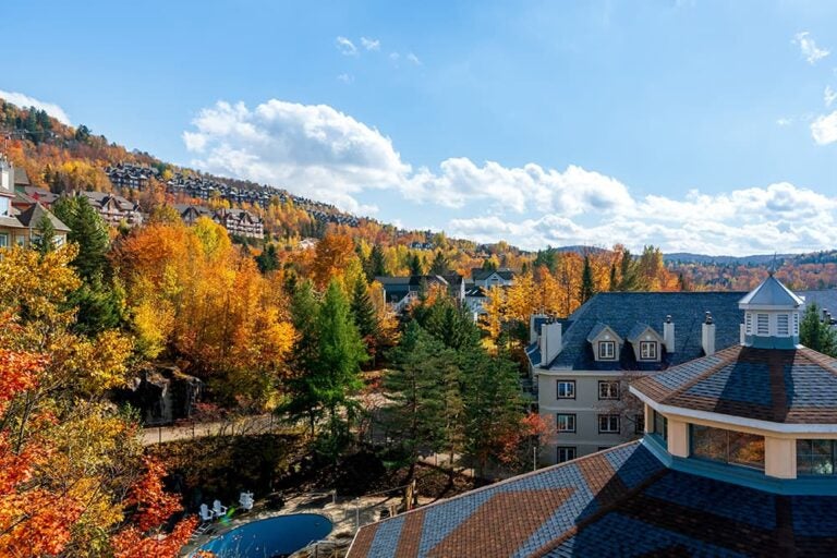 紅葉に包まれたカナダ・ケベックの街並みと森の景色。10月のメープル街道で秋の絶景を楽しむイメージ