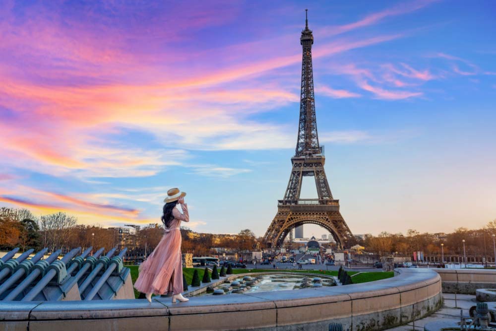 夕焼け空を背景にエッフェル塔を眺める女性の後ろ姿