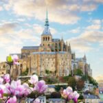 春の花越しに見えるモン・サン・ミッシェル修道院の全景写真。