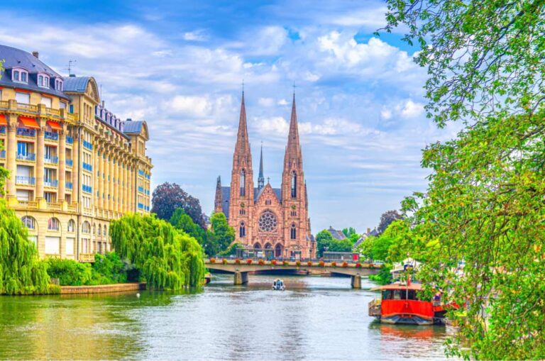 ストラスブールのイル川沿いに建つサン・ポール教会と周辺の歴史的建物、青空の下に広がる緑豊かな景色