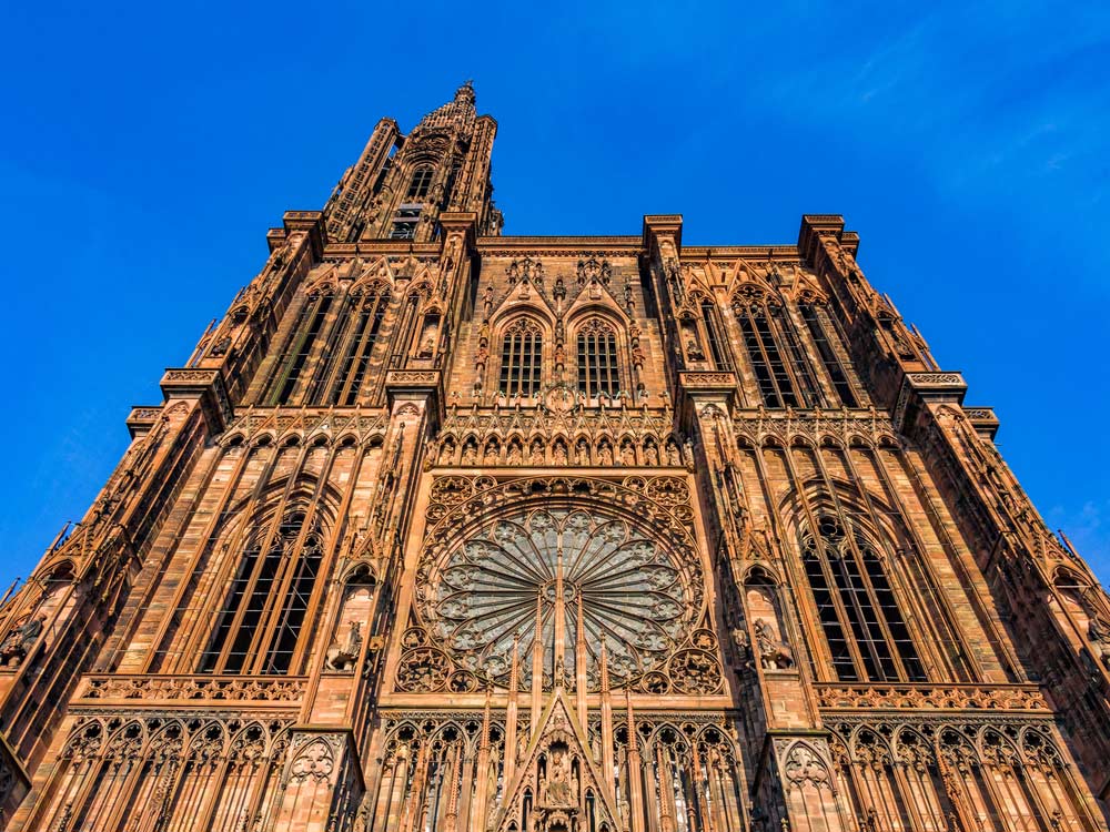 ストラスブールのノートルダム大聖堂を正面から見上げた写真。荘厳なゴシック建築と巨大なバラ窓が印象的な世界遺産の名所。