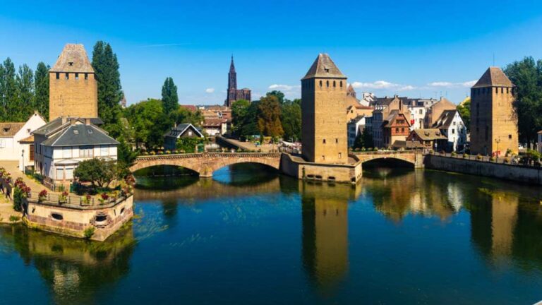 ストラスブール旧市街に架かるヴォーバン・ダムと三つの塔を望むパノラマ写真。水面に映る要塞橋と街並みが、歴史と景観美の融合を象徴している。