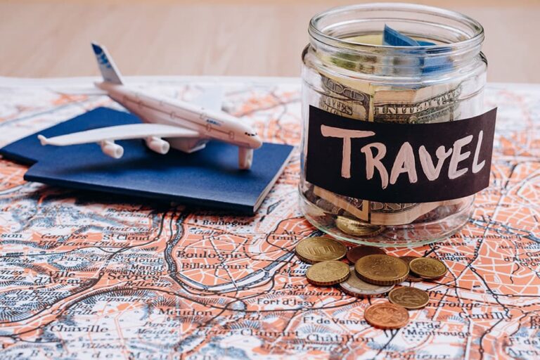 海外旅行の予算を準備するため、地図の上に貯金瓶・硬貨・飛行機の模型を置いた様子
