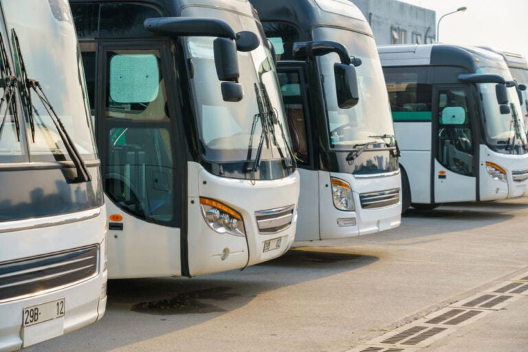 長距離バスの移動をイメージさせる、ターミナルに並ぶコーチバスの写真