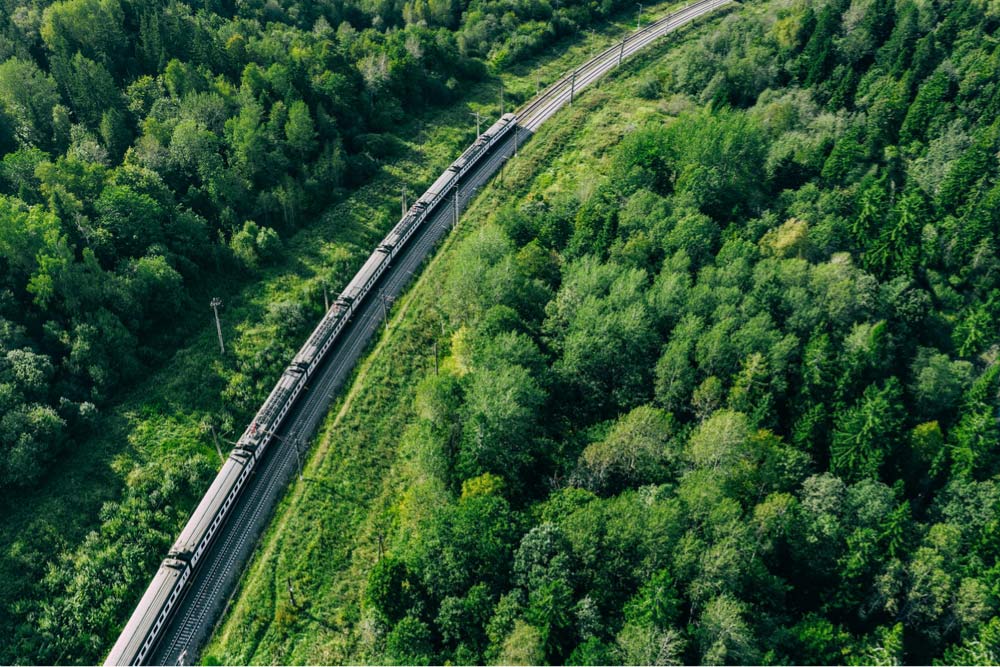 ロンドンからパリへ向かうユーロスターのような列車が緑豊かな森林の中を走る様子を上空から撮影した写真