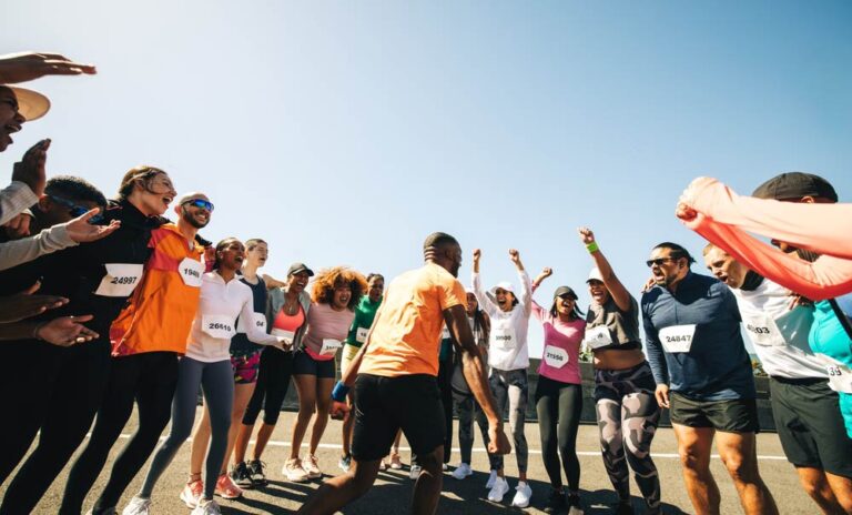 マラソン大会でチーム仲間を囲み、笑顔と歓声で応援するランナーたち。