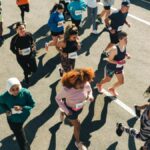 ゼッケンを付けた多様なランナーたちが舗装道路を駆け抜けるマラソン大会の様子。