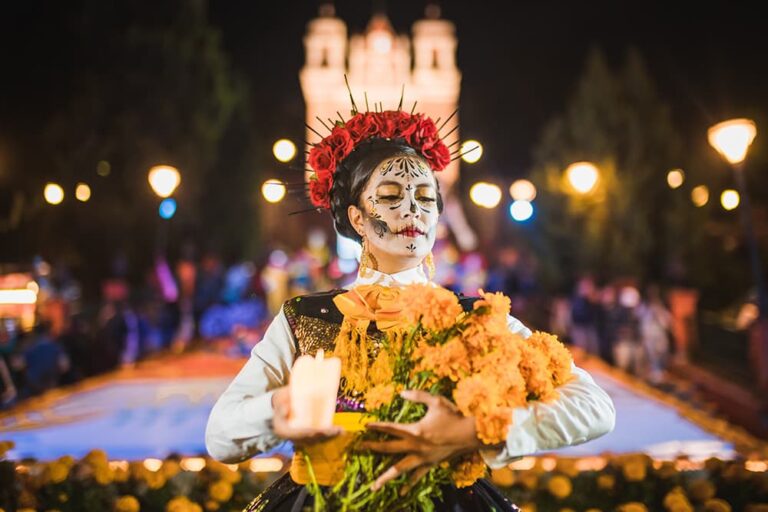 死者の日のメイクをした女性が花とキャンドルを持つ、10月末のメキシコシティで文化体験を楽しむ旅のイメージ