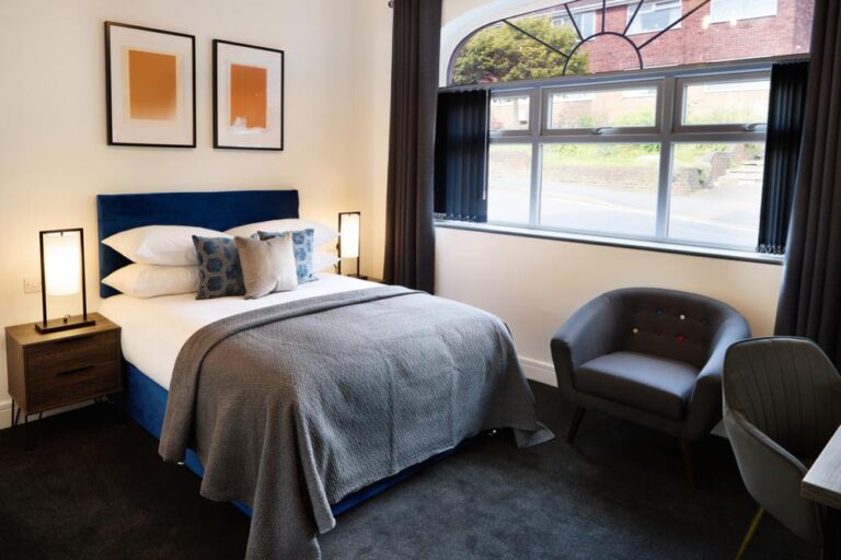 ダブルベッドと大きな窓を備えた、モダンで落ち着いた雰囲気のホテル客室。