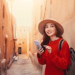 モロッコの伝統的な街並みでスマートフォンを使う女性旅行者
