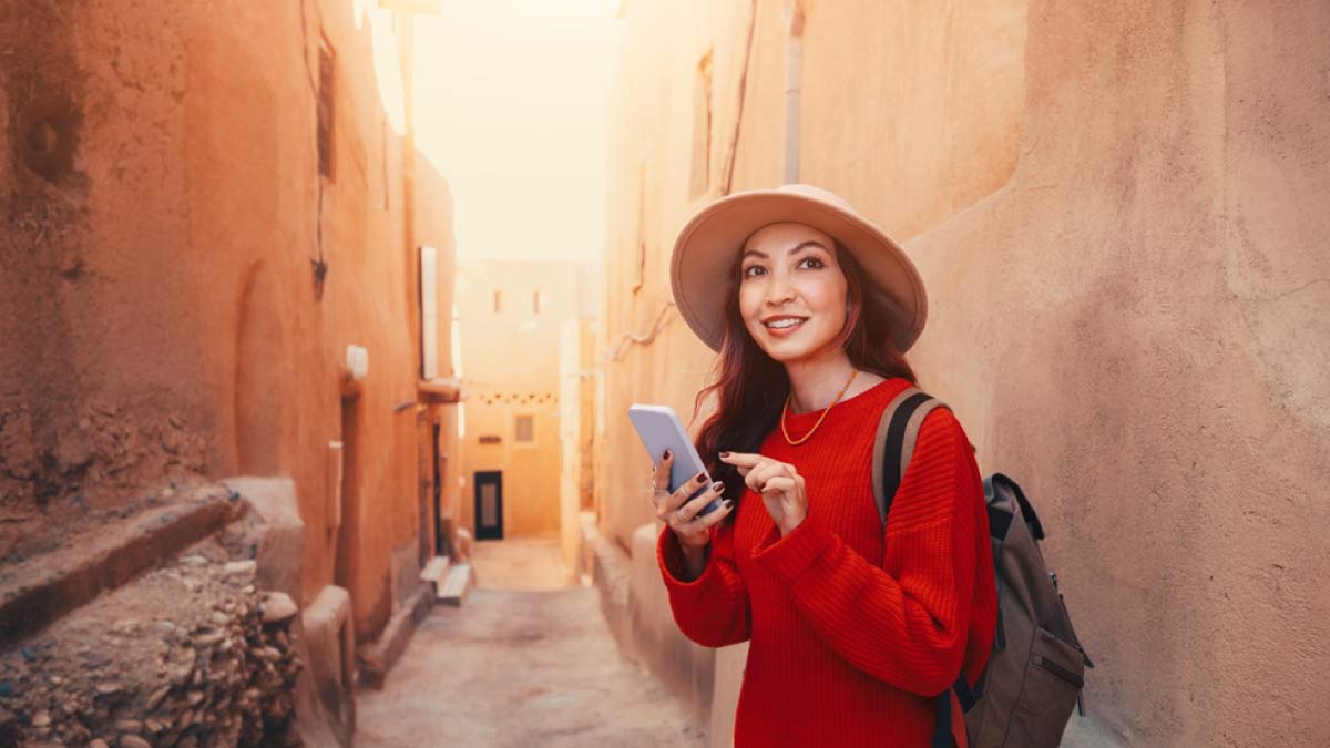 モロッコの伝統的な街並みでスマートフォンを使う女性旅行者