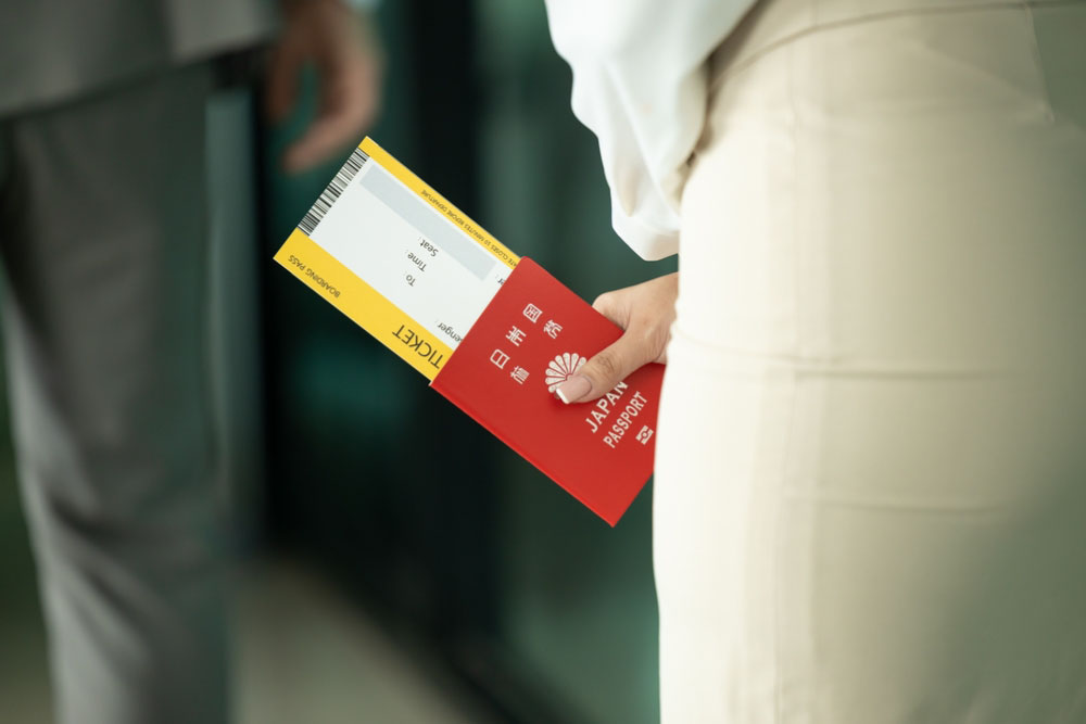 日本のパスポートと航空券を手に持つ女性の写真。