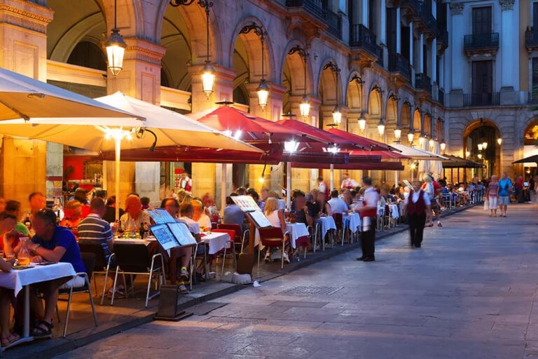 9月の海外旅行におすすめのバルセロナで、広場のテラス席に人々が集まる夜のグルメ風景