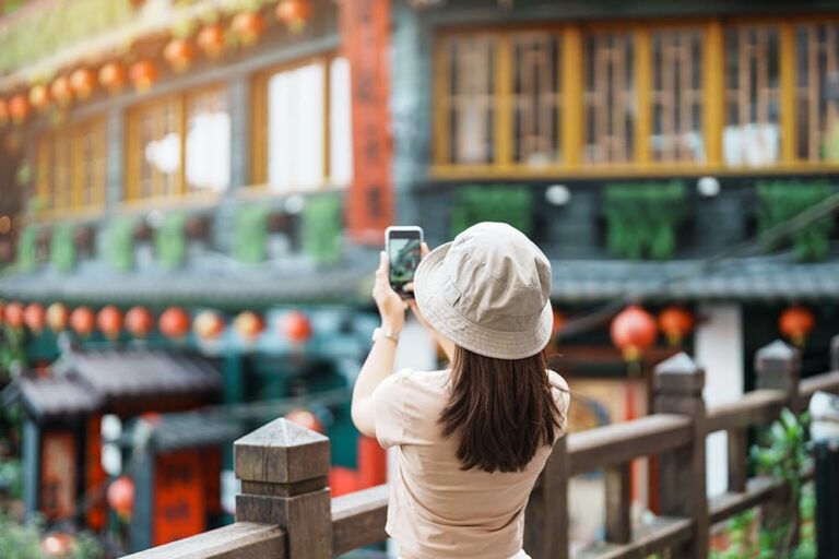 台湾・台北近郊の九份で、旅行者が提灯の並ぶ街並みをスマートフォンで撮影している様子