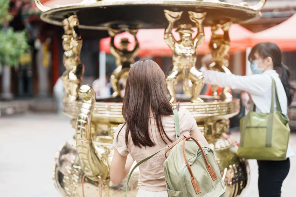 台湾の寺院で金色の大香炉を眺める女性の後ろ姿