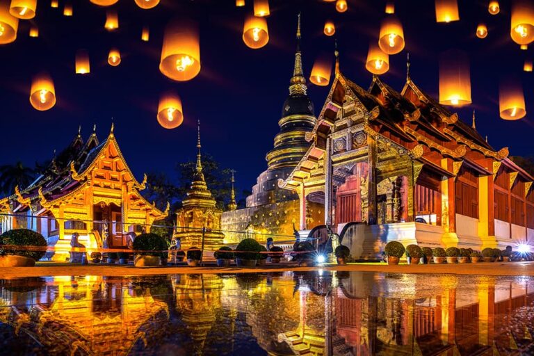 タイ・チェンマイの寺院で、夜空にランタンが浮かぶ11月のランタン祭りの風景