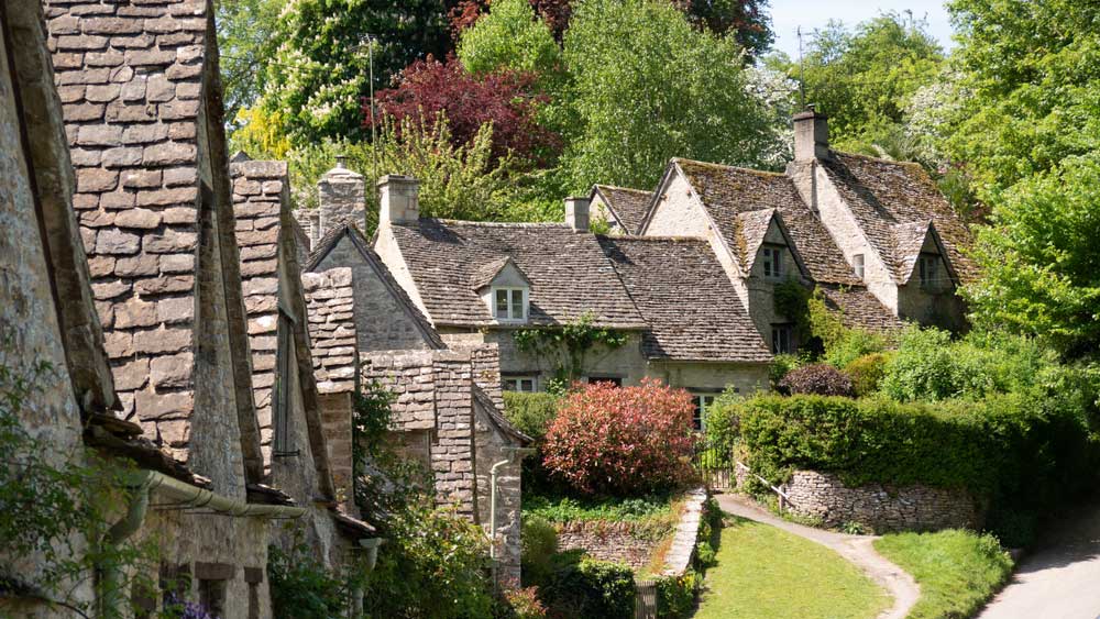 「英国一美しい村」と称されるバイブリーの石造りコテージと緑豊かな小道を写した写真