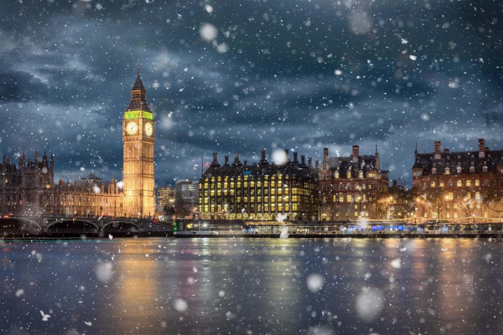 夜のロンドンで雪が舞う中ライトアップされたビッグ・ベンの写真。