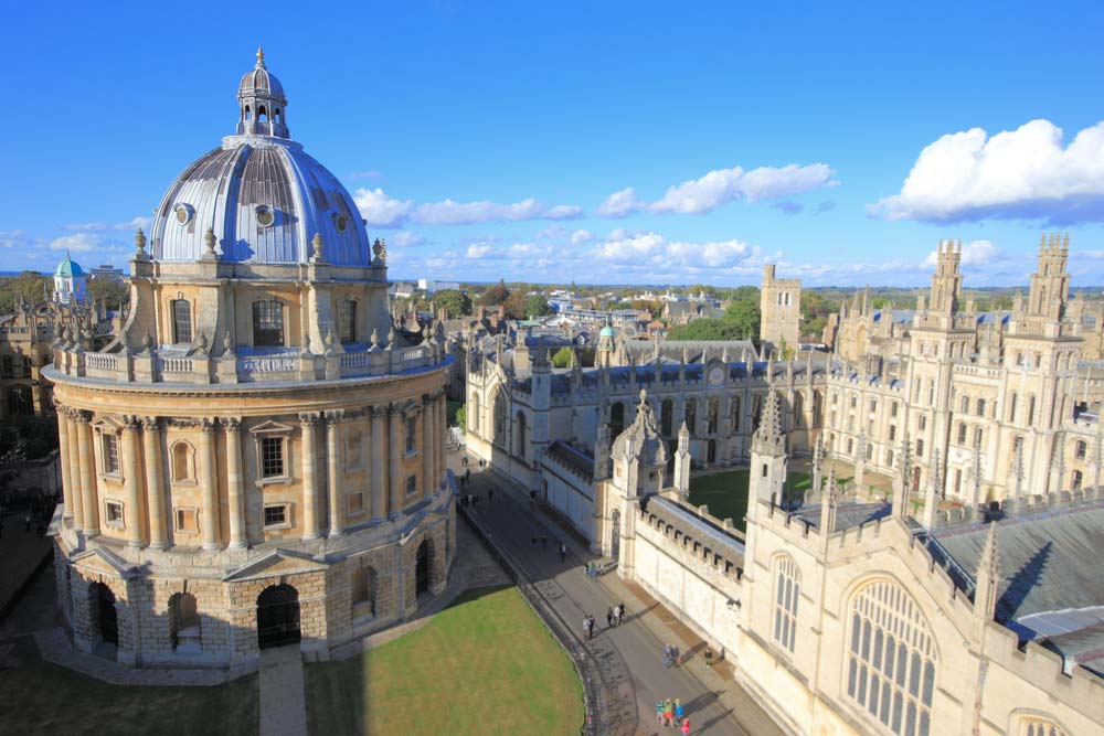 晴天の下、イギリス・オックスフォード大学のラドクリフ・カメラとオール・ソウルズ・カレッジの美しい建築が広がる風景。