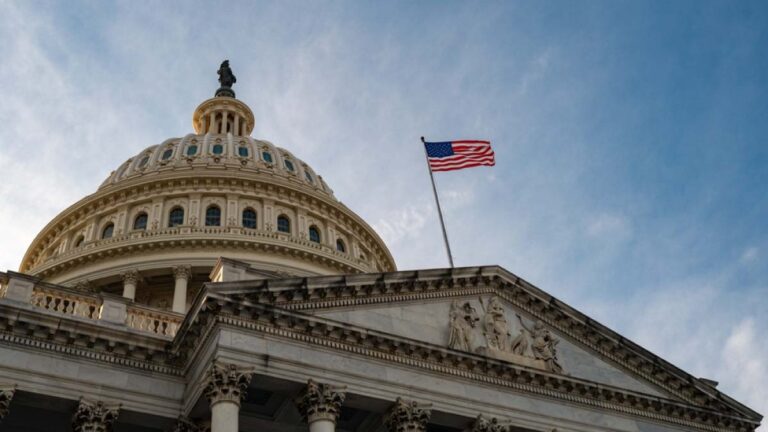 アメリカ国旗が掲げられた米国連邦議会議事堂のドームとファサードを見上げる構図。
