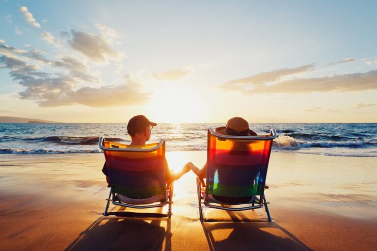 ハワイのビーチで旅行者が夕日を眺めながら、年末前のゆったりしたリゾート時間を過ごす様子