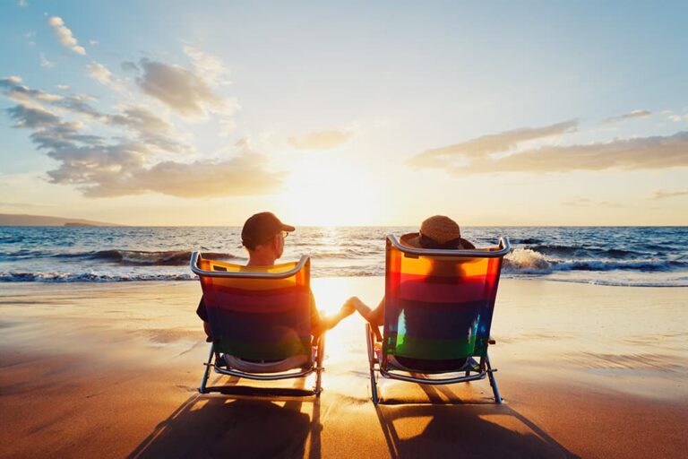 9月の5連休におすすめのハワイで、夕暮れのビーチに座って海を眺める旅行者の後ろ姿
