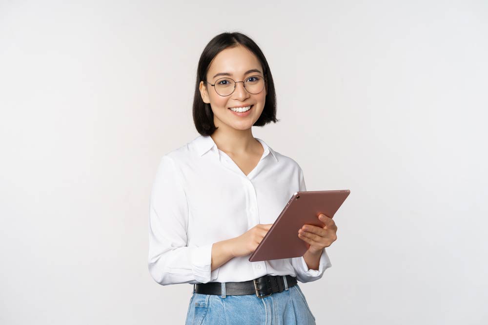 アジア人女性がタブレットを持って立っている。