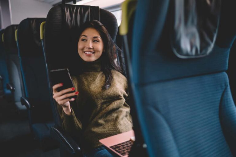 長距離バスの座席でスマホを見ながらリラックスする女性。