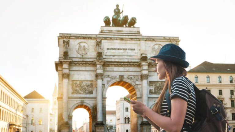 ミュンヘンの凱旋門「ジーゲストーア」を背景に観光マップを持つ女性旅行者
