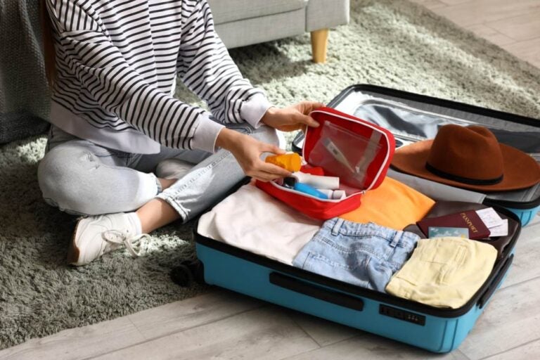 旅行用スーツケースに服や必需品を詰める女性