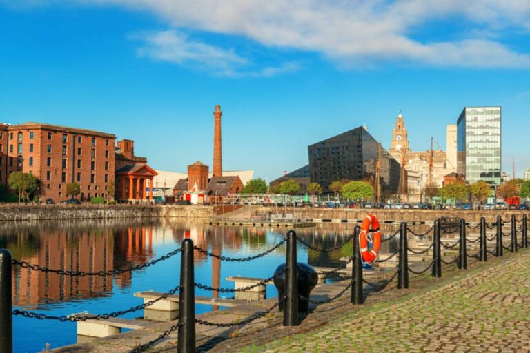 リバプールのアルバート・ドック。赤レンガ倉庫と近代的な建築が並び、青空と水面に映える風景。