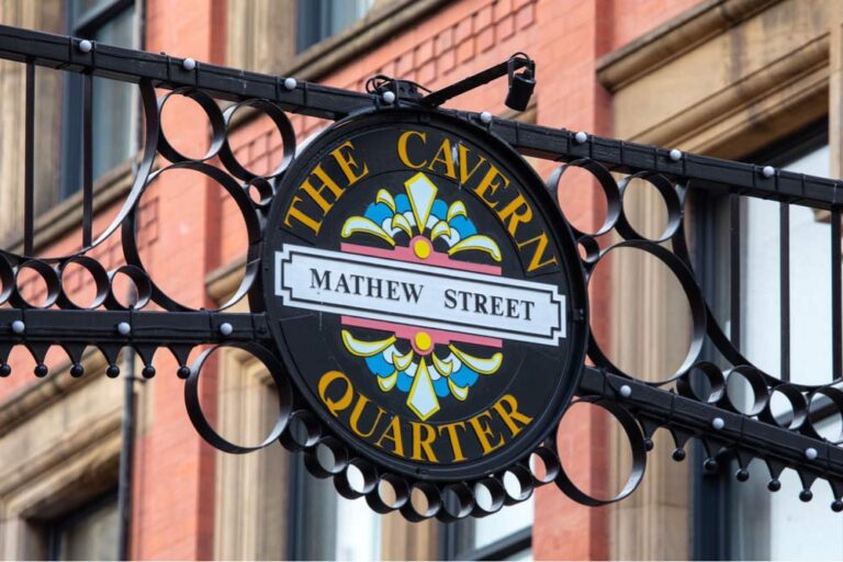 リバプールのマシュー・ストリートにあるキャバーンクォーターの装飾サイン。レンガ造りの建物を背景にカラフルなデザインが映える。