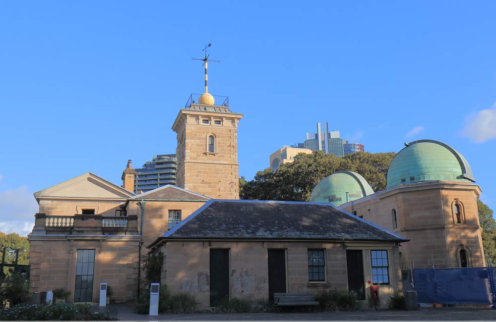 シドニー天文台の歴史的な建物と緑色のドーム屋根、背景に広がる高層ビル群