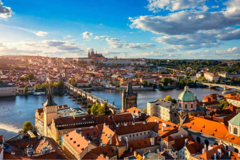 ヴルタヴァ川に架かるカレル橋と、その奥に広がるプラハ城を望むプラハ歴史地区の全景。赤い屋根と石造りの街並みが美しい、世界遺産に登録された中世都市。