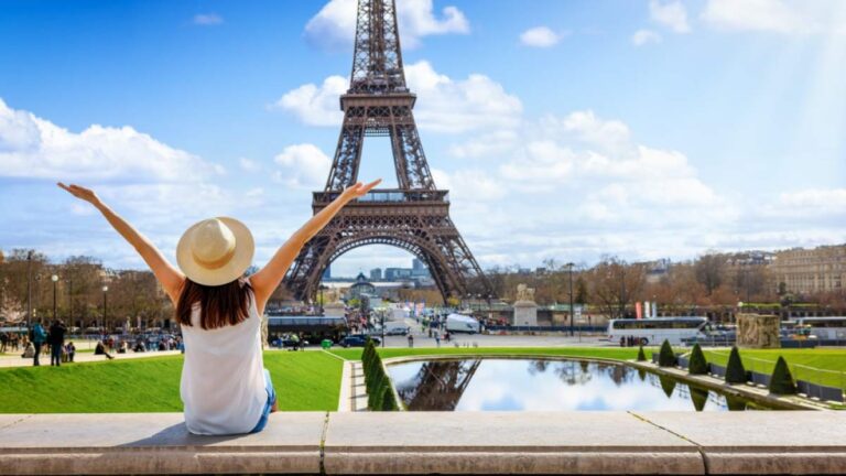 晴れた日のパリでエッフェル塔を眺める観光客が春の服装で気候を楽しんでいる様子